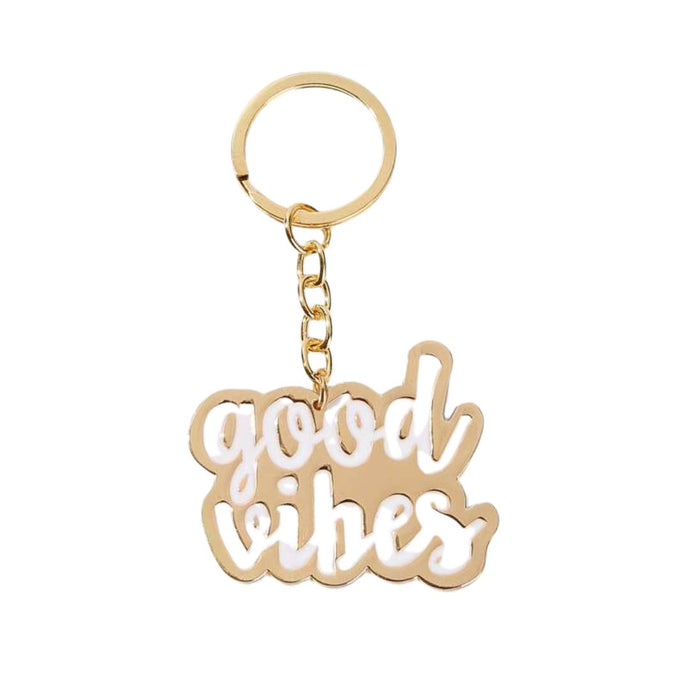 Gold metal keyring with the words good vibes in white enamel