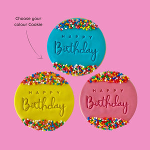 Three happy birthday cookies with blue, pink and yellow icing, decorated with sprinkles on a pinkbackground