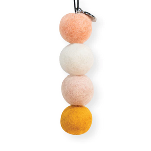 four pink, white yellow and peach coloured felt balls hanging from an elastic with silver charm