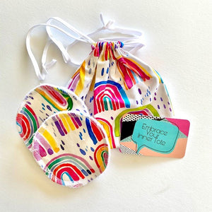 handmade breast pads in a bright rainbow fabric together with it's own travel/was tote