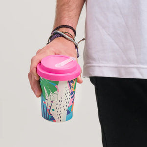 LNWY Travel Cup with artwork from Sirmano with pink screw top lid bot made from 100% plant fibre  held by male hand