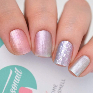 Mermaid themed nail wraps shown on nails and hand with a package in the background