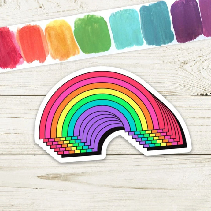 A repeated rainbow design sticker on a timber background and colour swatch as the background