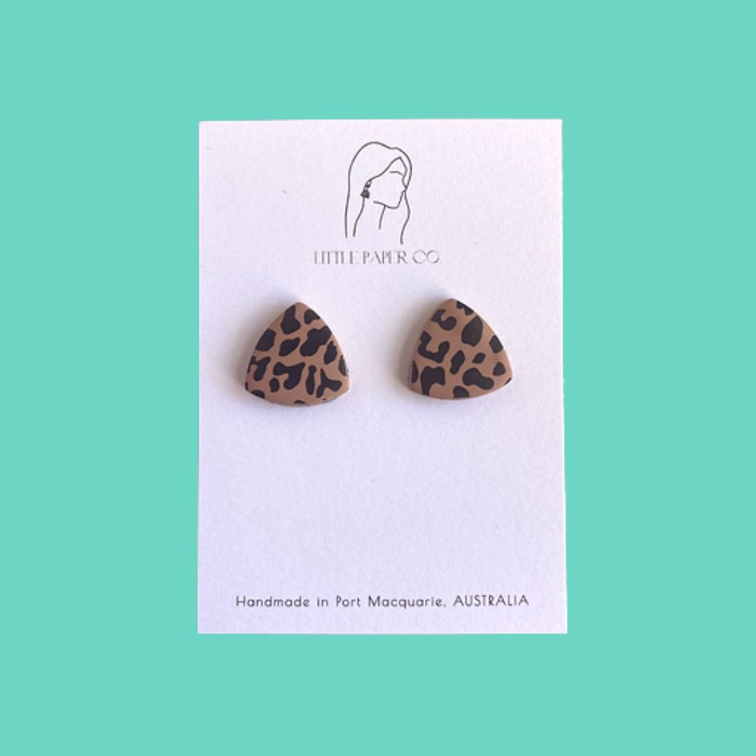 Leopard print handmade polymer clay triangular stud earrings on white backing card and an aqua background